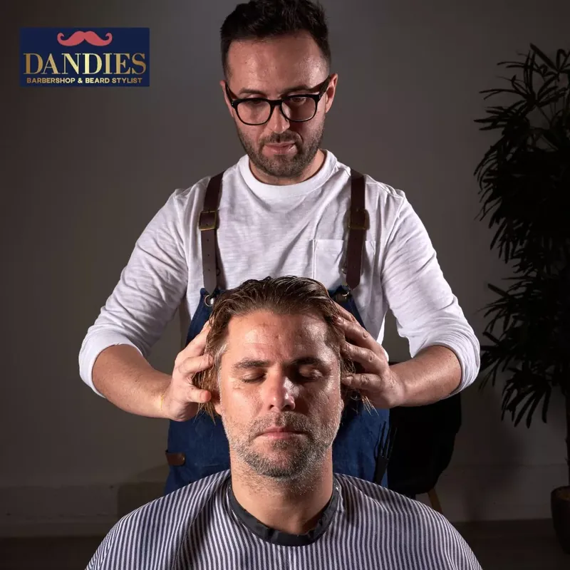Barber giving a client an Indian head massage, gentle pressure on the scalp, at Dandies