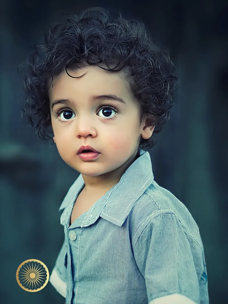 Toddler with soft dark curls in a denim shirt